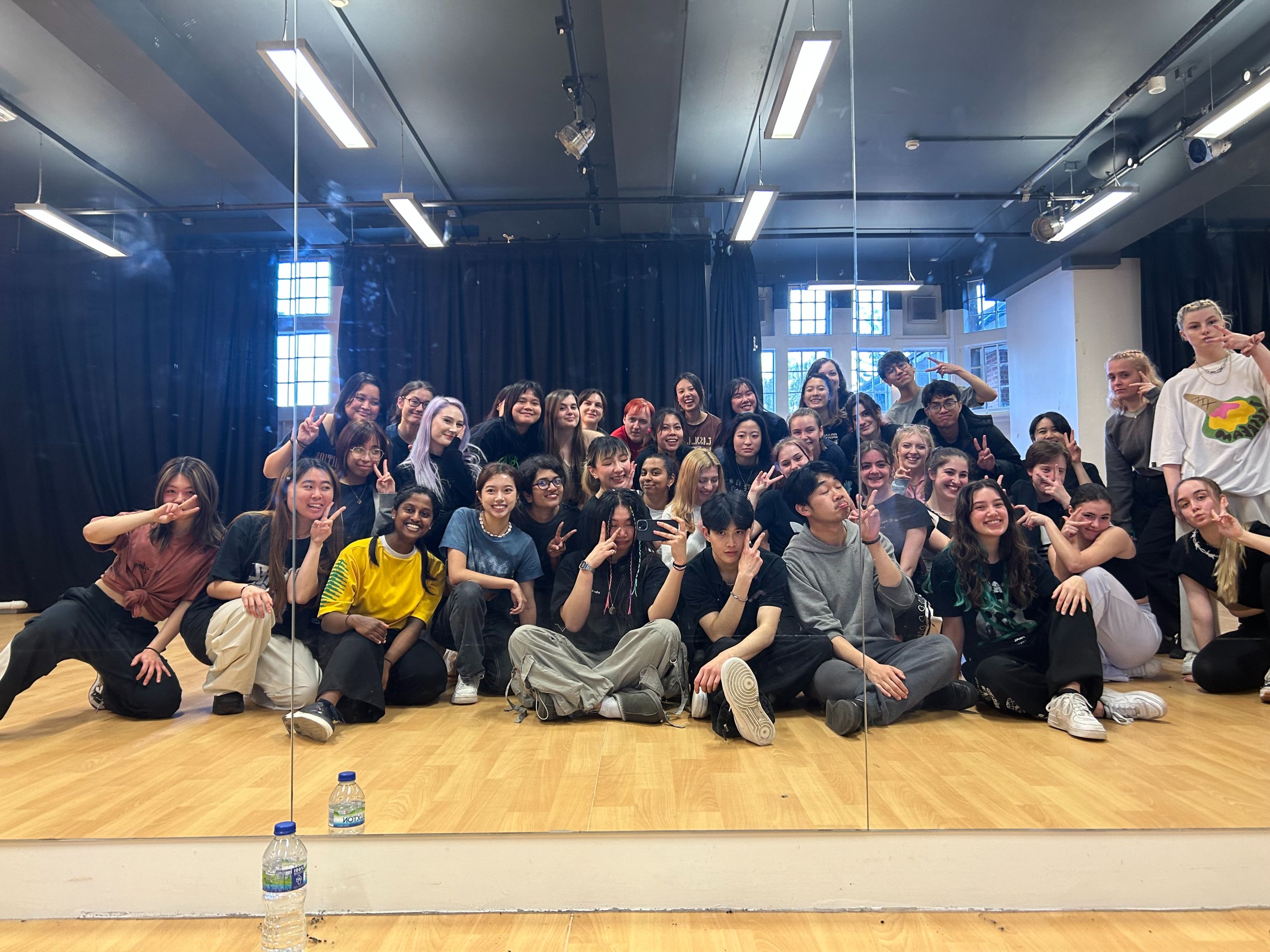 A diverse group of students facing a mirror in various poses, taking a phone selfie