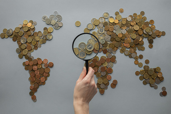 World map composed of coins under a magnifying glass