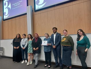 Ten PGR finalists stand at the front of a lecture theatre