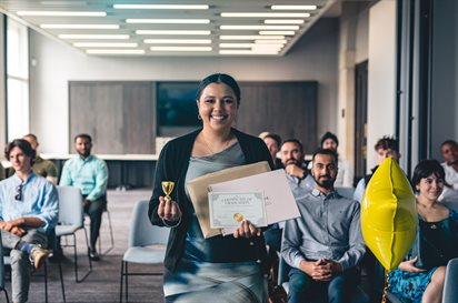 Person standing smiling with an award.