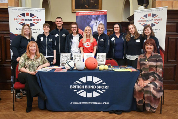 Team GB standing behind a welcome stand table for British Blind Sport