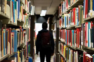 student standing amongst library shelves