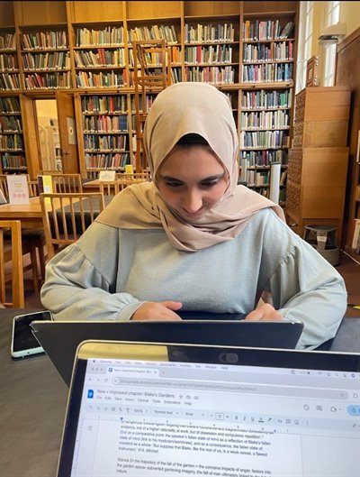 Female student wearing a hijab typing into her laptop