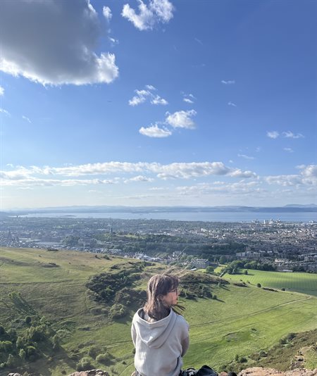 A girl sits on top of a hill