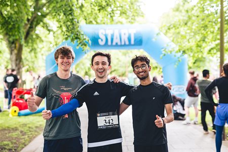 A group of boys smile under the start line for the campus 3k