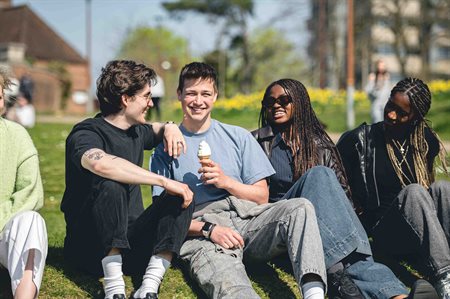 A group of students relax on campus, one of them holding an ice cream
