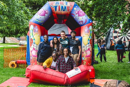 A group of students smile at the camera in an inflatable tunnel