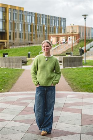 Student Content Shaper Alice smiles at the camera in front of the Main Library