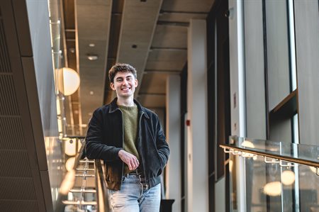 Student Dean stands on the Teaching and Learning building stairs.