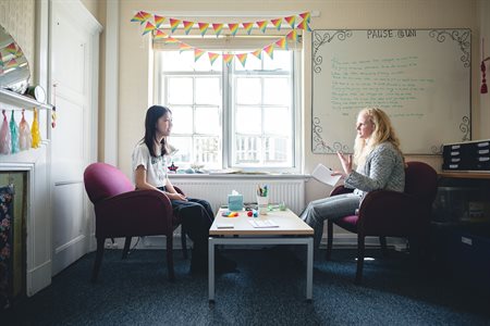 A student and a Pause practitioner chat in a meeting room.