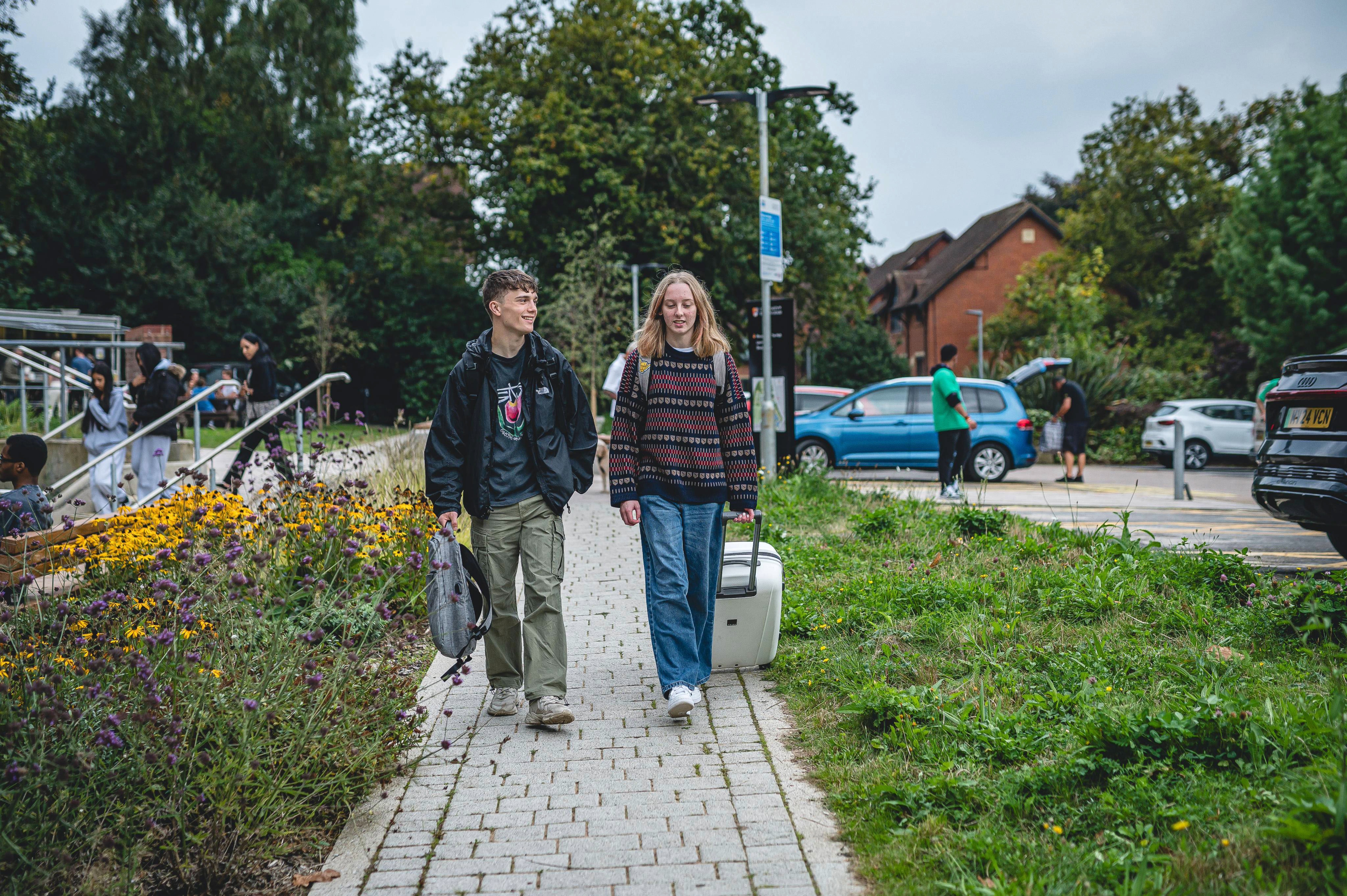 Students walking to campus with their bags and suitcases