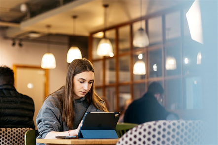 A person sitting at a table using a tablet__Description automatically generated