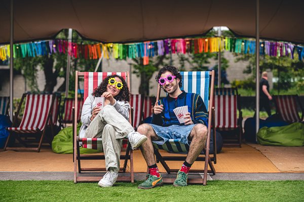 A female and male student sit on deckchairs holding popcorn boxes